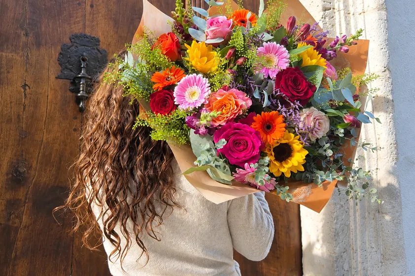 Bouquet coloré tenu devant une façade en pierre
