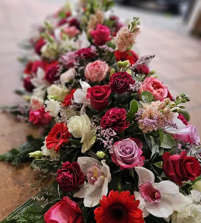 Composition allongée de roses rouges et de fleurs variées