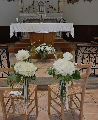 Bouquets blancs au bout des bancs d’une église pour une cérémonie de mariage