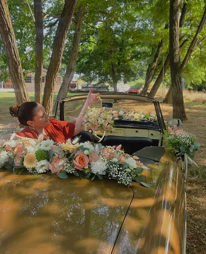 Voiture de mariage décorée de fleurs, la mariée et son bouquet à bord