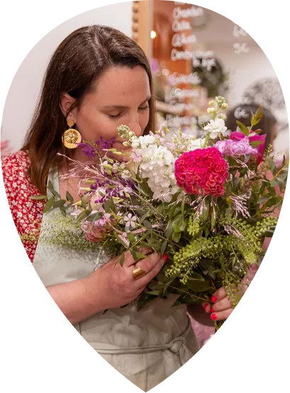 Charlène respirant un bouquet de fleurs fraîches dans sa boutique